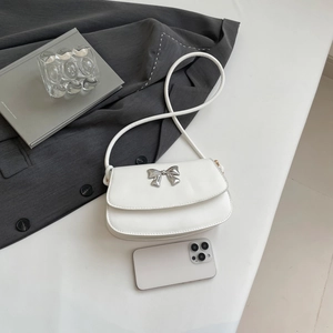 Close-up of a white leather bag featuring a silver mirror metal bow detail and shoulder strap
