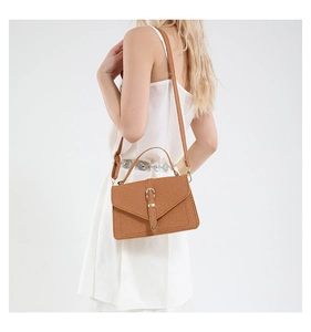 Chic brown woven shoulder bag with envelope flap and adjustable strap on a model