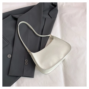 Close-up of cream minimalist underarm bag with smooth finish and gold metal hardware