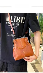 Close-up of vintage brown leather handbag with metal clasp and white contrast stitching detail