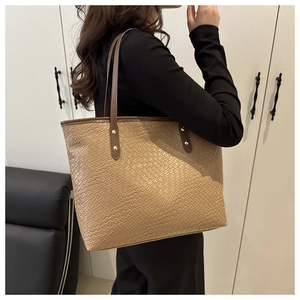 Detail shot of khaki woven crocodile texture and golden rivet on large tote bag
