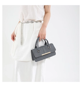 Detail of grey textured fabric handbag featuring minimalist design and gold metal accents
