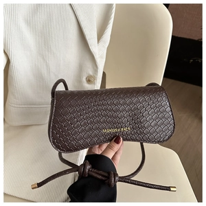 Detailed view of dark brown woven texture handbag with gold hardware and knot strap