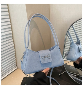 Détail du sac baguette bleu clair avec boucle nœud argenté et tissu en sergé