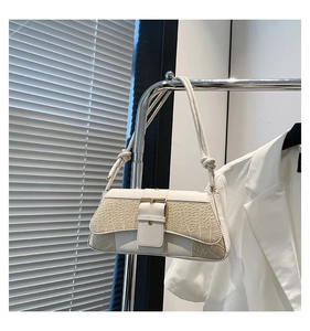 Detail of cream white faux leather shoulder bag with crocodile pattern and gold buckle