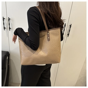 Detail view of brown woven texture and leather handle on a large commuter tote bag