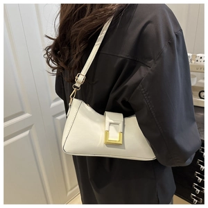 Détail du sac baguette blanc avec boucle dorée et bandoulière portée à l'épaule