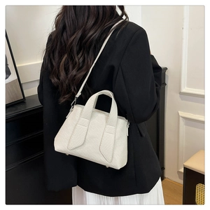 Detail of cream tote bag featuring twill texture, dual handles and adjustable strap