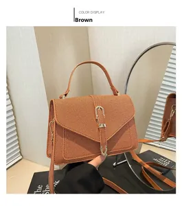 Detailed close-up of brown textured fabric crossbody bag with gold buckle and top handle