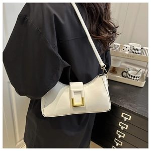 Détail d'un sac porté épaule minimaliste blanc avec boucle dorée sur le bras du modèle