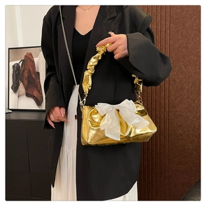 Detail of metallic gold crossbody bag with white organza bow and chic cloud handle