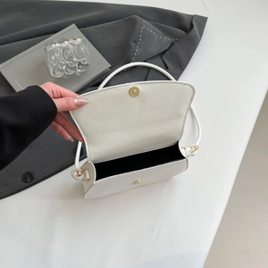 Detail of white leather shoulder bag with gold magnetic buckle and ribbon knot strap
