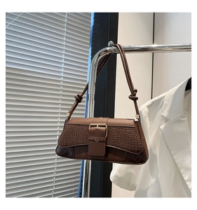 Detail of dark brown faux leather bag with crocodile texture and gold buckle hardware