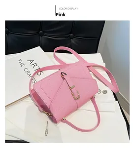 Detail of pink crossbody bag with horizontal woven texture and golden U-shaped metal buckle