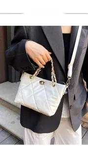 Close-up of white quilted leather shoulder bag featuring gold chain and turn-lock