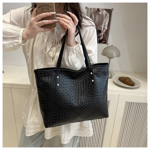 Detail of black woven tote bag with gold rivet accents and premium textured finish