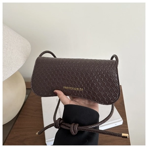 Close-up of dark brown woven texture crossbody bag with gold text and knotted strap detail