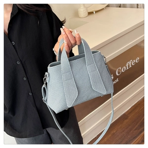 Close-up of light blue woven texture tote bag held by a model in a stylish cafe