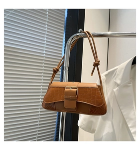 Detail of brown crocodile pattern shoulder bag with golden buckle on a metal hanger