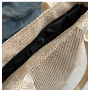 Dettaglio di una cerniera nera su una borsa tote in velluto a coste bianco crema