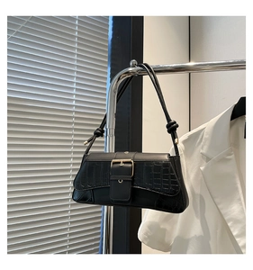 Detail of black faux leather baguette bag with crocodile texture and gold square buckle