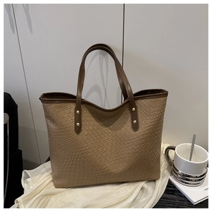 Detail showing the brown woven texture and gold metal rivets on a large tote bag