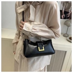 Détail d'un sac baguette noir brillant avec boucle dorée et bandoulière fixe