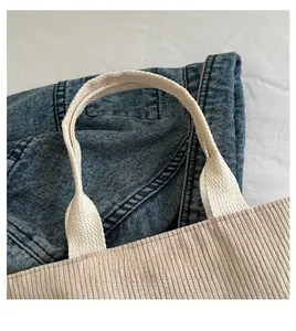 Dettaglio della borsa tote in velluto a coste beige con trama a righe e manico rinforzato