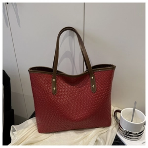 Detail of red woven texture on a large tote bag with dark brown handles and rivets