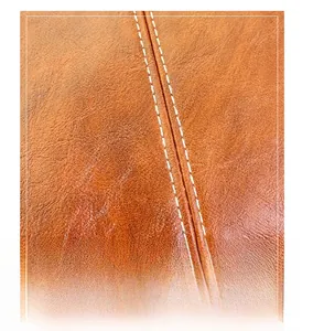 Macro detail of high-quality brown lychee leather with precise contrast double stitching