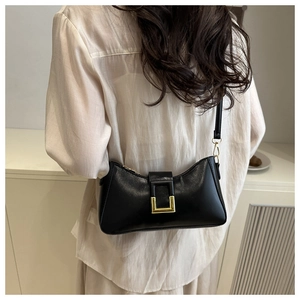 Sac bandoulière noir minimaliste avec boucle dorée porté par un mannequin de dos