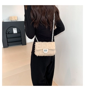 Détail d'un sac bandoulière en tweed beige avec chaîne argentée et fermoir sur un mannequin