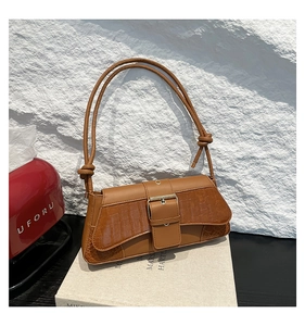 Detail showing the brown faux crocodile texture and large metal buckle on the shoulder bag