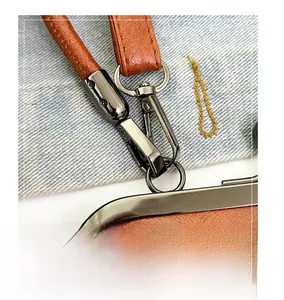 Detail of gunmetal polished metal hook and D-ring on brown lychee texture leather strap