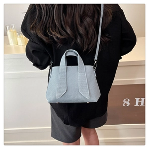 Close-up of light blue textured tote bag with metal base studs and detachable strap