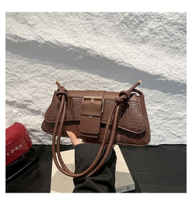 Detail of dark brown faux crocodile shoulder bag featuring gold buckle and twisted strap