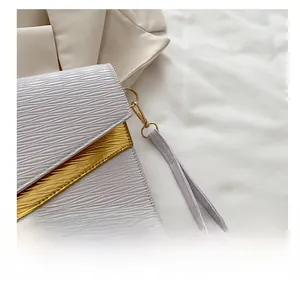 Detail of purple wavy texture envelope bag with gold hardware and detachable wrist strap