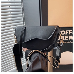 Détail du sac selle noir mat avec rabat incurvé et deux bandoulières amovibles