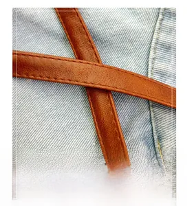 Detail of durable brown leather shoulder strap with neat stitching on blue denim fabric