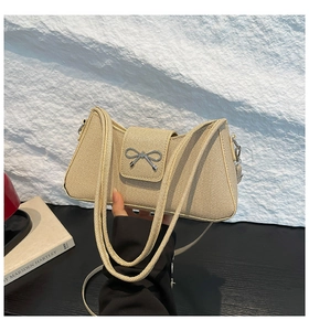 Détail du sac baguette tissé beige avec nœud en métal argenté et fines bandoulières