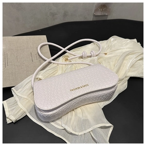 Detail shot of white woven texture shoulder bag with golden fashion text on silk cloth