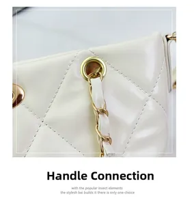 Detailed close-up of golden metal rings and leather chain handle on white quilted tote bag