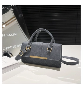 Detail shot of gray denim texture handbag with gold metal hardware and adjustable strap