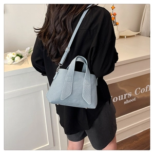 Close-up of light blue striped tote bag featuring woven texture and silver metal feet