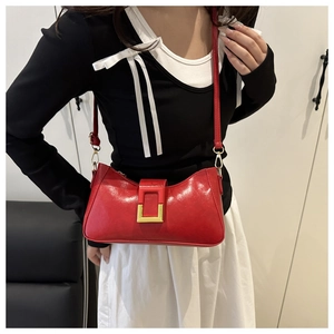 Détail du sac baguette rouge brillant avec grande boucle dorée et bandoulière fine