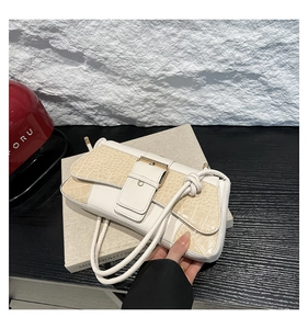 Detail of white crocodile embossed shoulder bag with metallic buckle and flap closure
