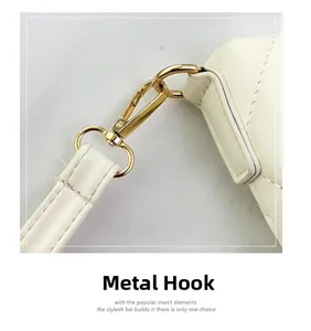 Detail of golden hardware hook and quilted leather texture on cream shoulder bag