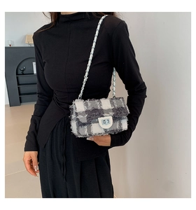 Détail du sac bandoulière en toile à carreaux avec bords effilochés et chaîne en métal
