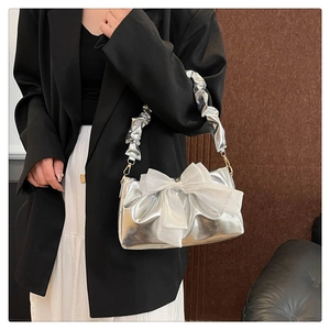 Detail of silver metallic handbag with a large white organza bow and ruched cloud handle