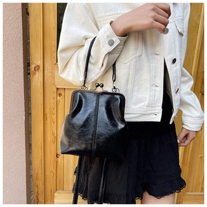 Close-up of a vintage black kiss-lock handbag with shiny wrinkled leather and metal clasp